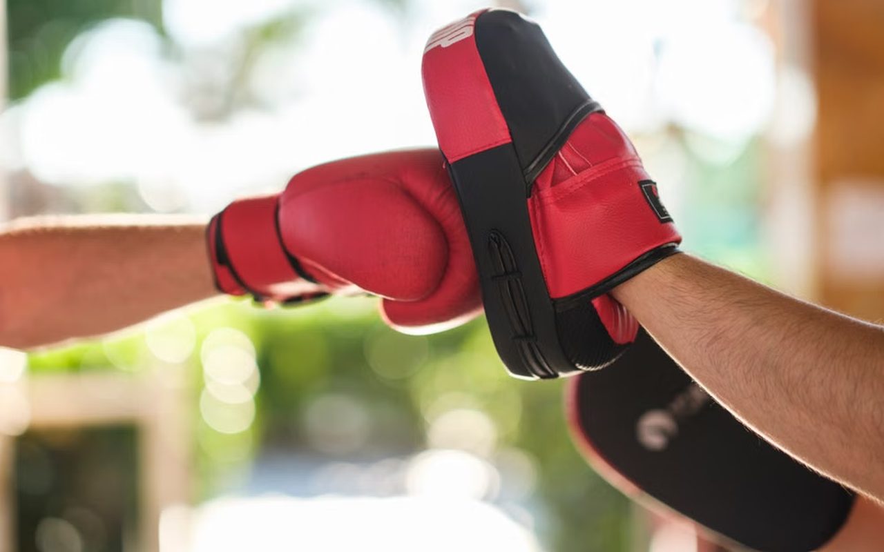 Red boxing glove pressed against a training pad at an outdoor gym