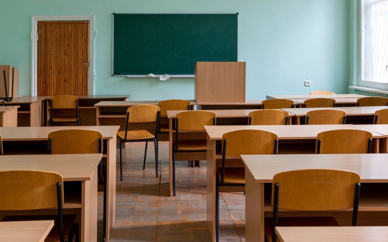 Empty classroom with rows of wooden desks and a chalkboard