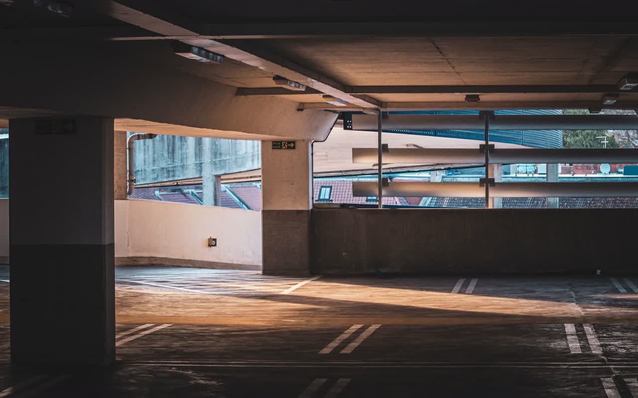 A sunlit multistorey parking garage with empty parking spaces