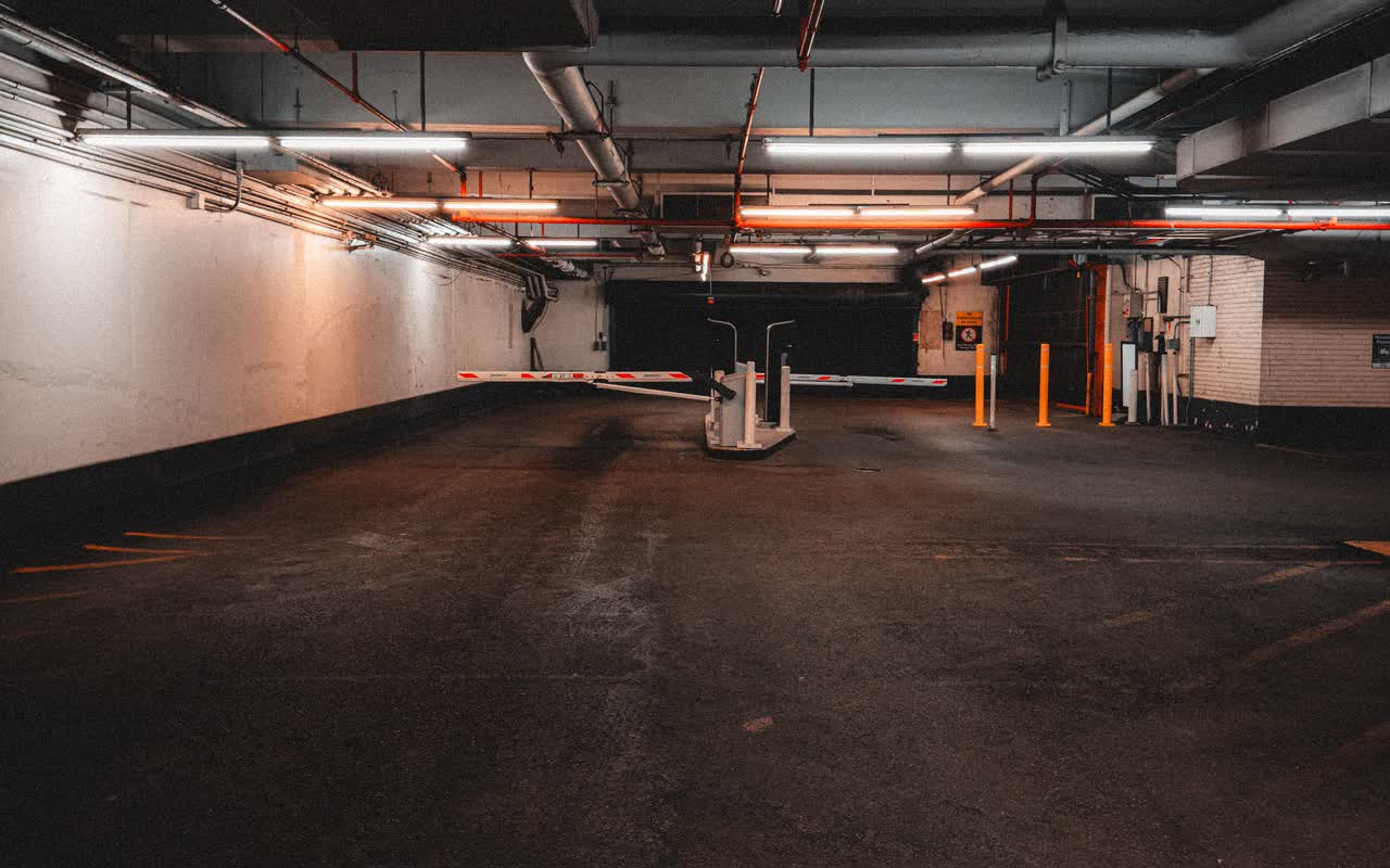 Empty underground parking garage with concrete pillars and overhead pipes