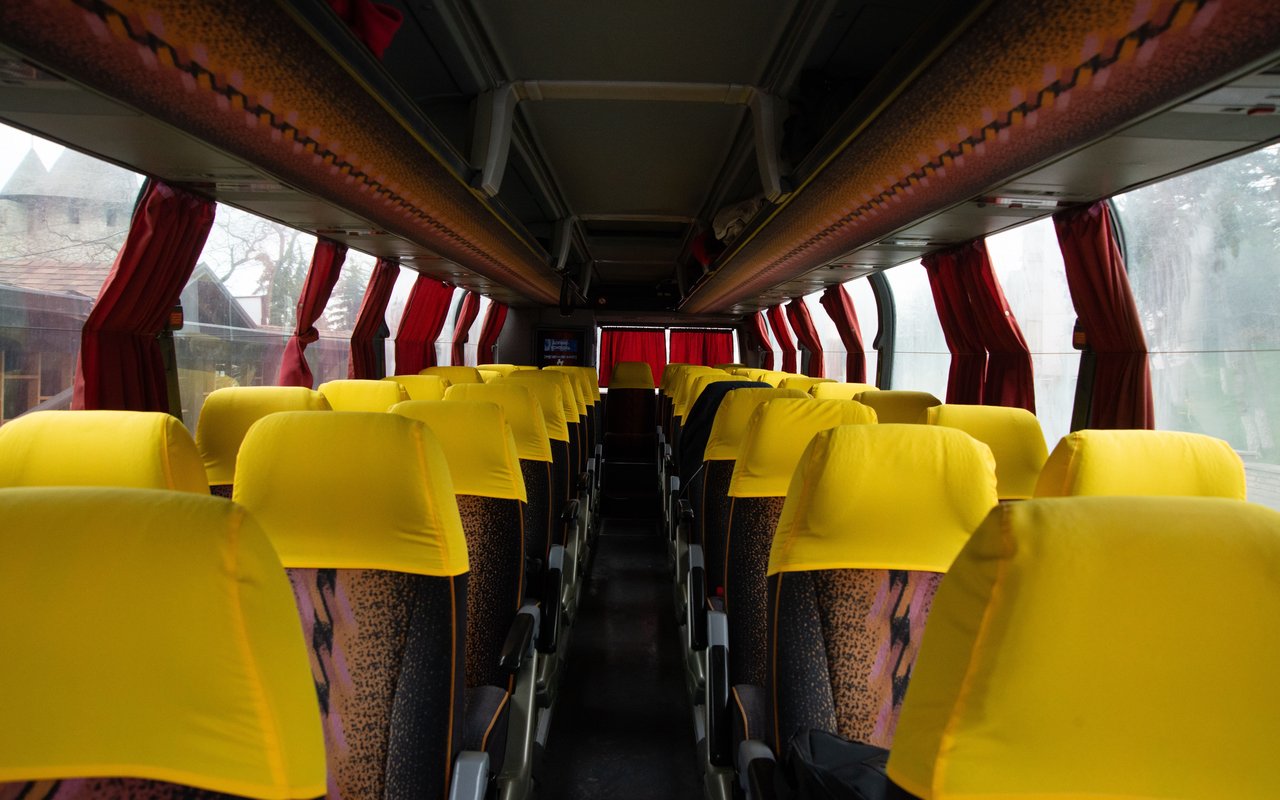 Empty coach interior with rows of yellow-covered passenger seats