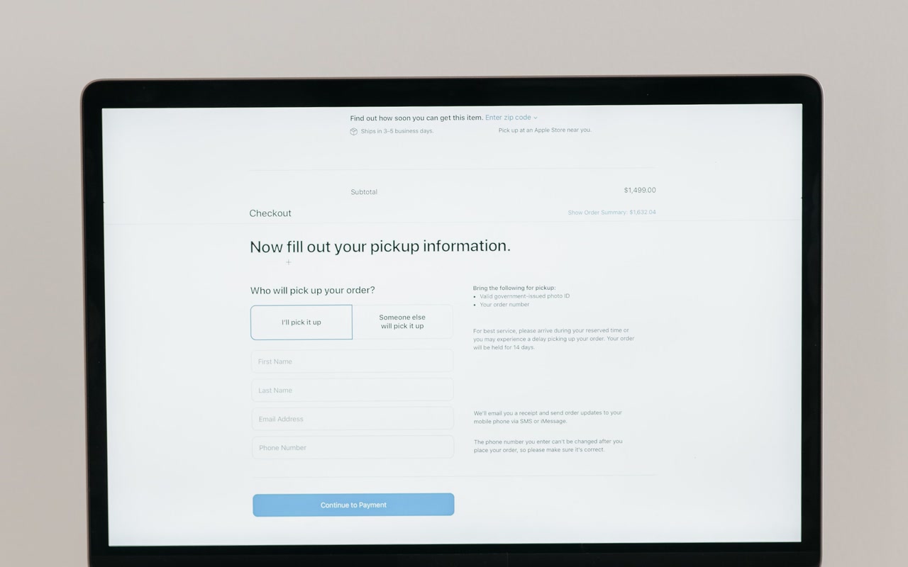 Open laptop displaying a generic online checkout form on a plain wooden table