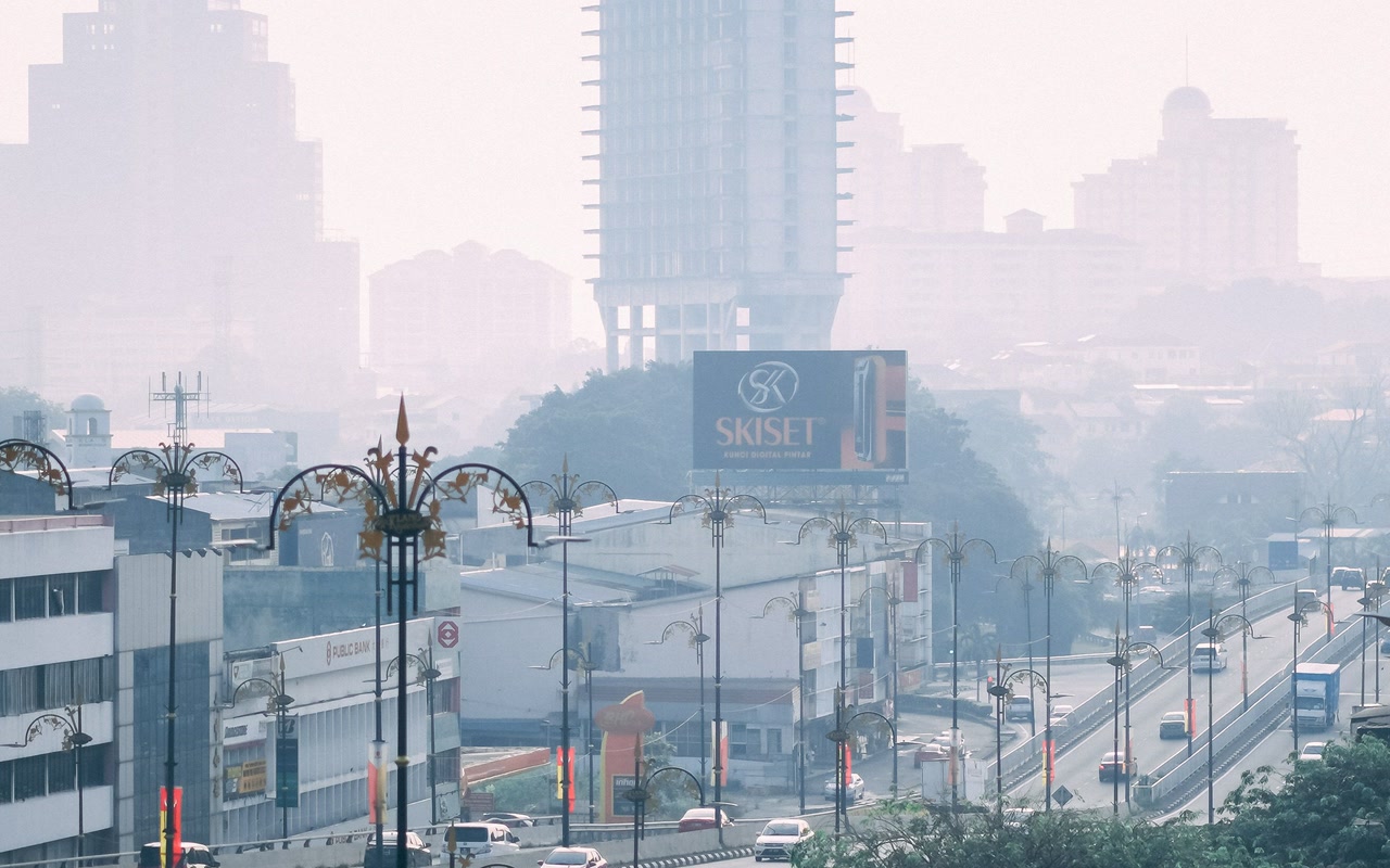Traffic on an overpass beneath a fog-softened Klang skyline