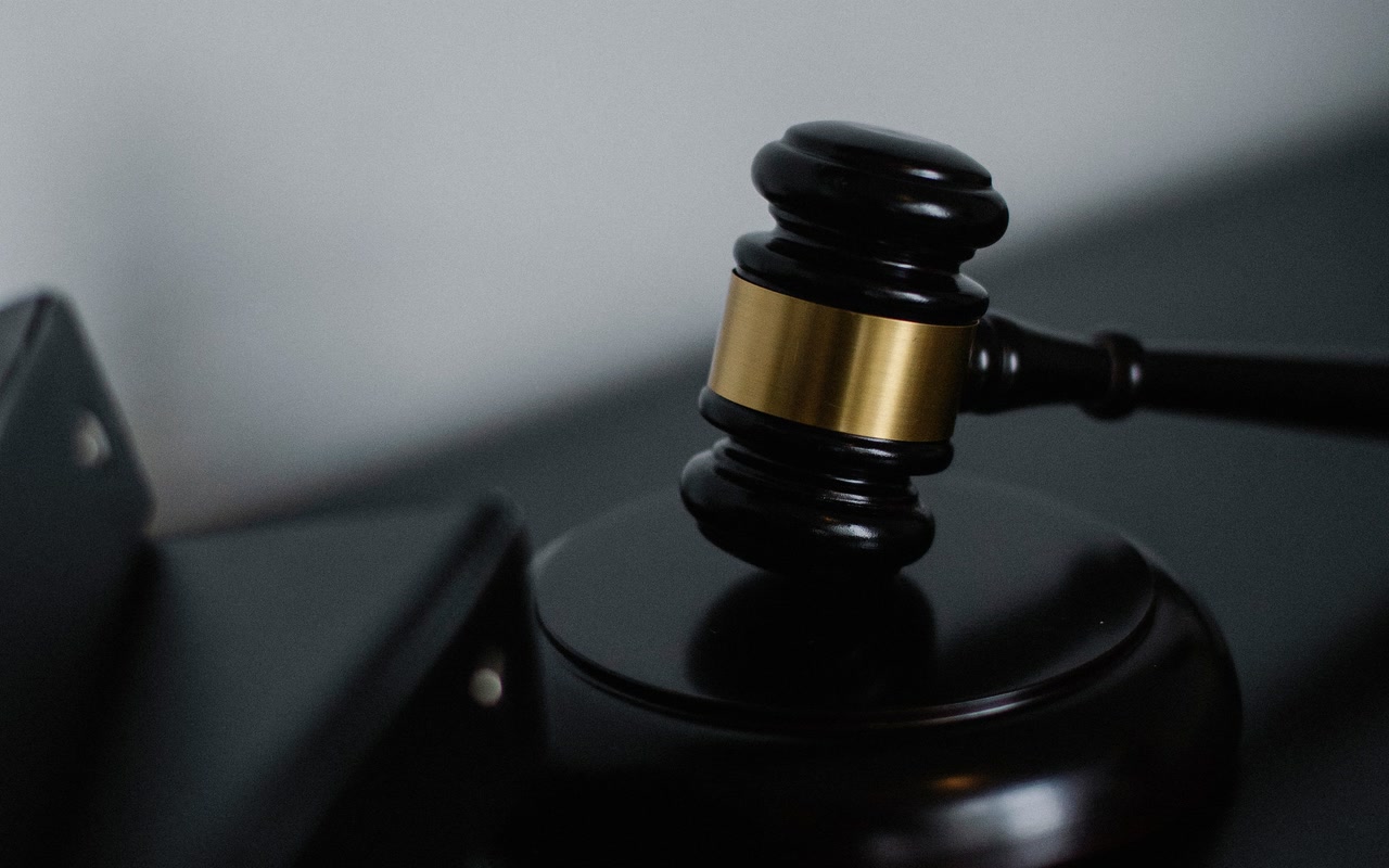 Plain wooden gavel beside closed document folders on a courtroom desk