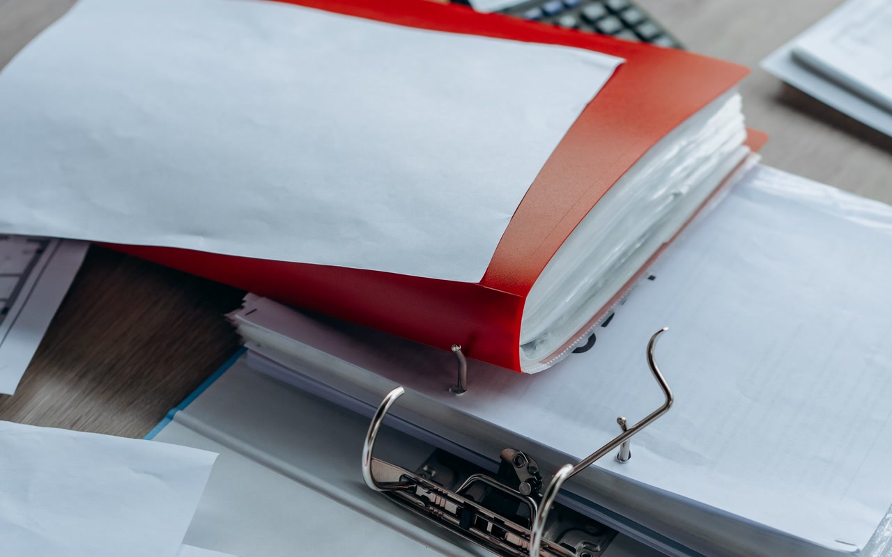 Open ring binders with blank paperwork stacked on an office desk