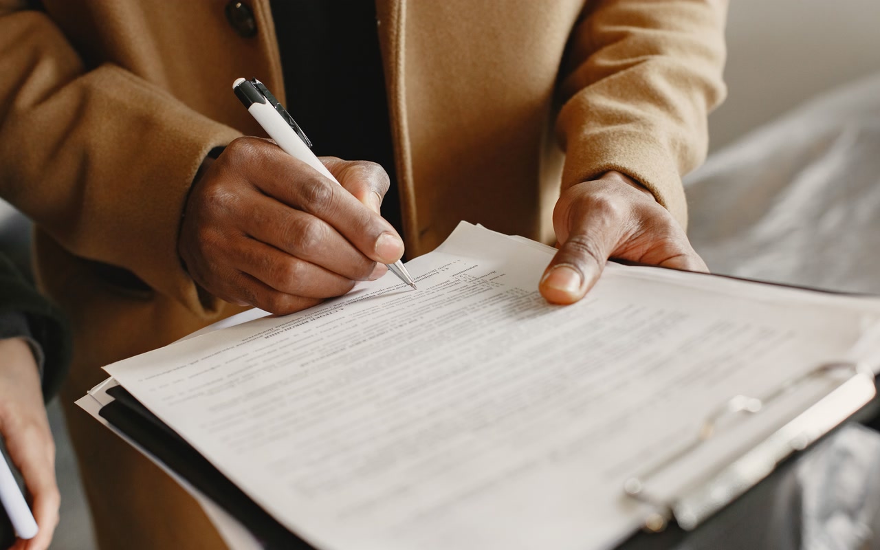 Close-up of an adult signing a generic document on a clipboard