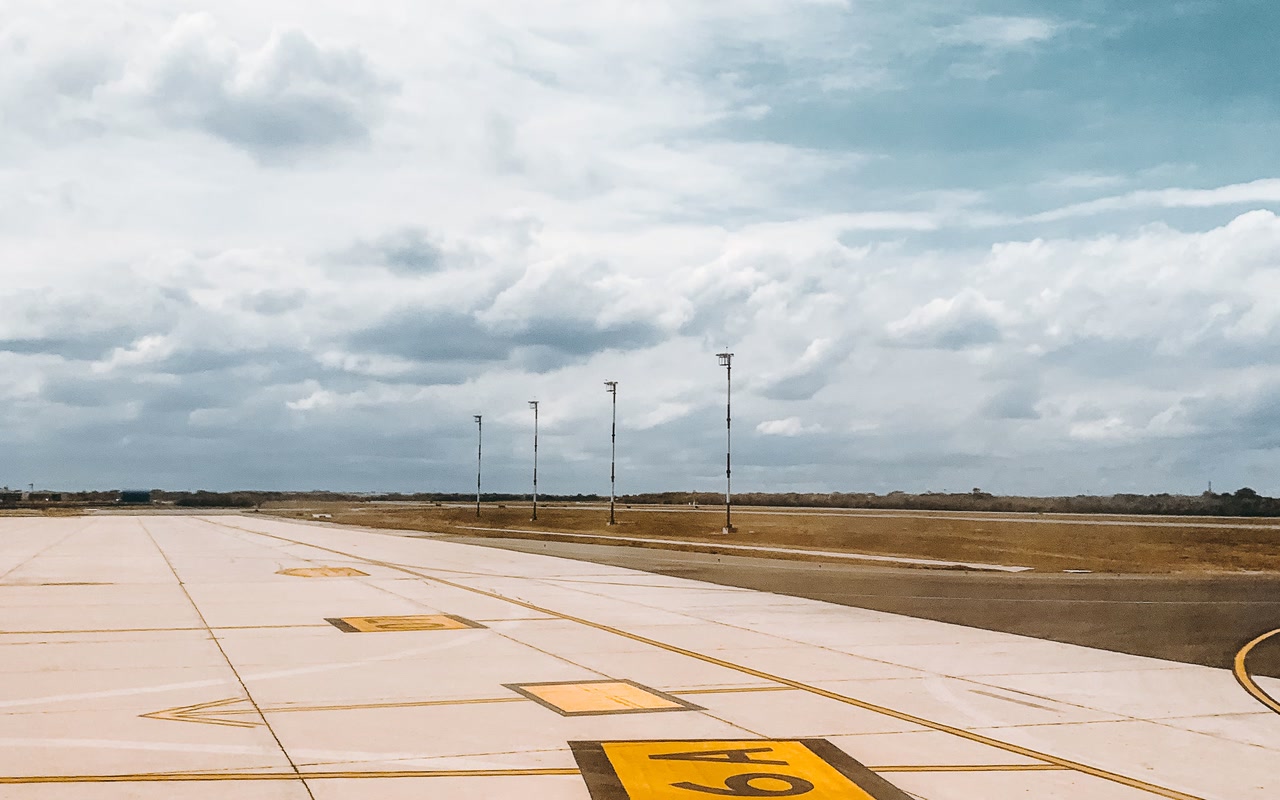 An empty airport runway beneath a partly cloudy sky
