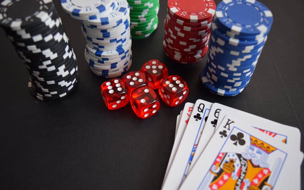 Playing cards, poker chips and red dice arranged on a green gaming table