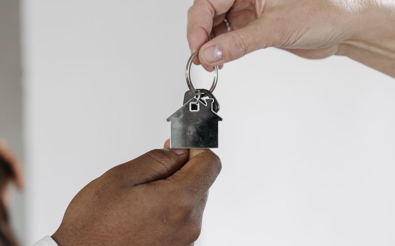 Two adults exchanging a keyring with a house-shaped pendant