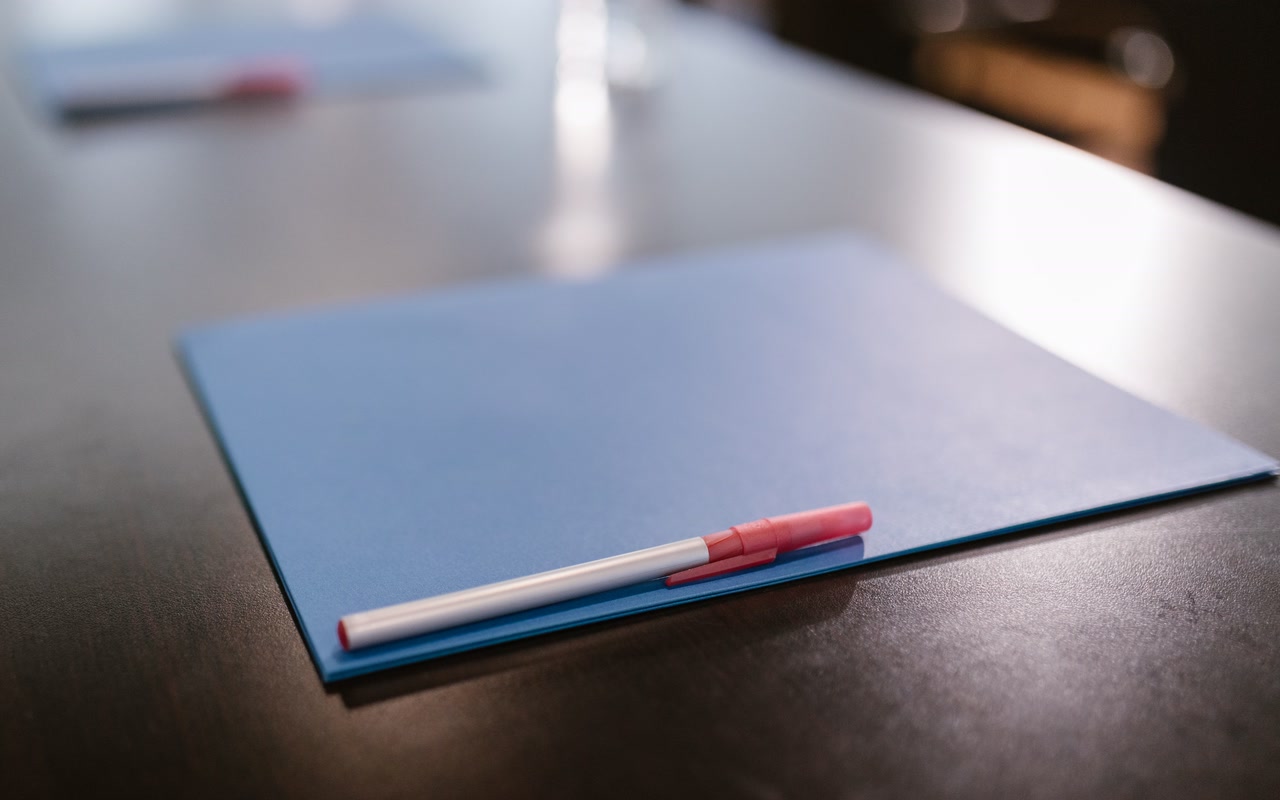 Blue document folder and black pen on a clean office table