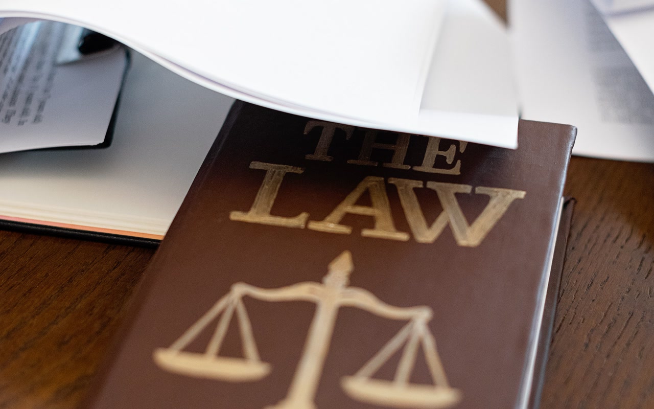 Law book resting on a wooden desk covered with papers