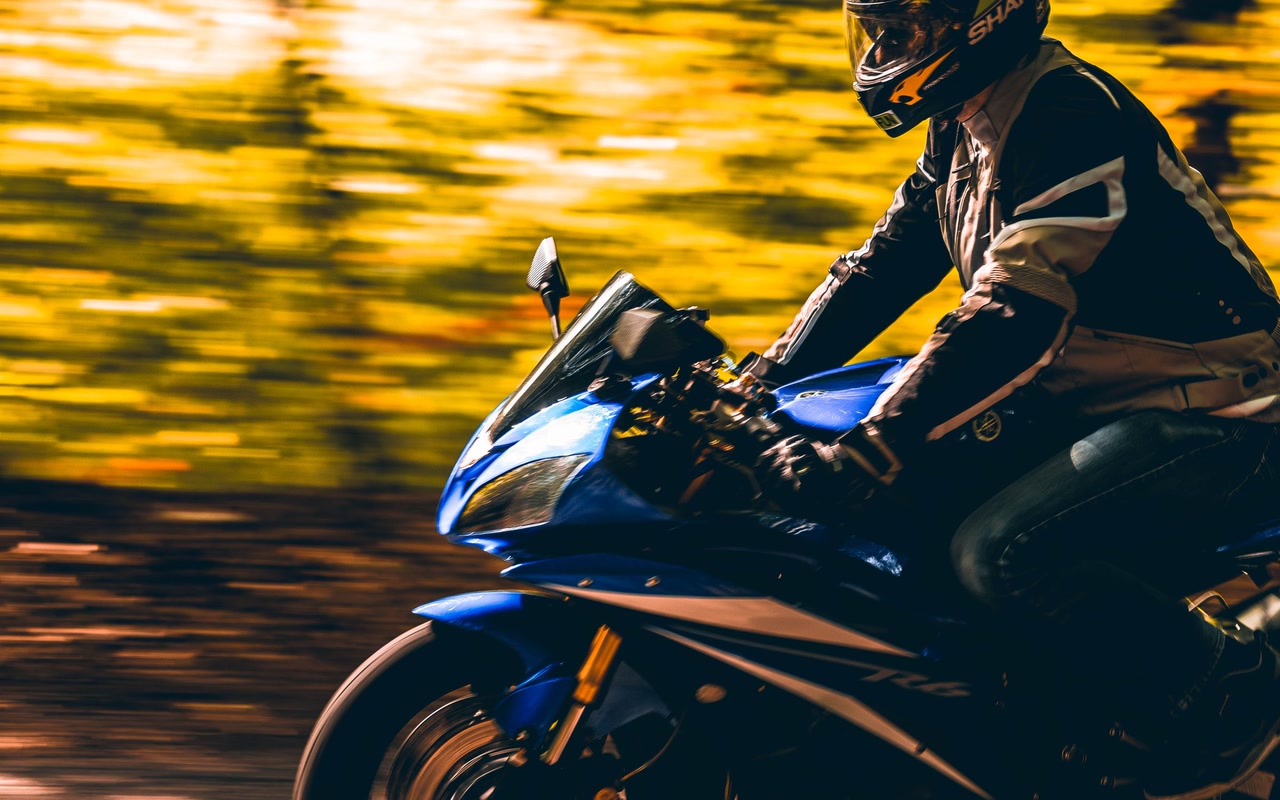 Helmeted motorcyclist riding through a curved forest road