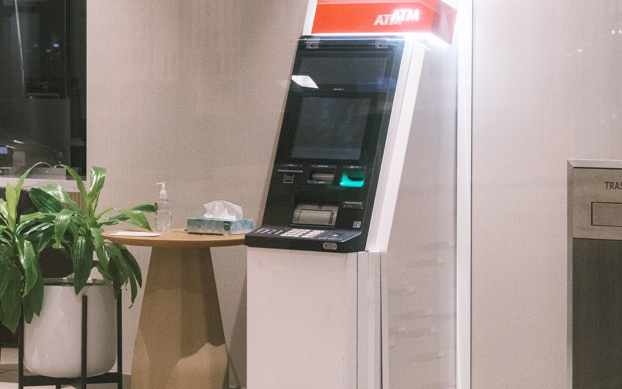 ATM machine beside a potted plant in a quiet bank lobby