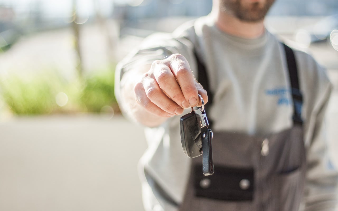 Close-up of a hand holding a plain car key against a softly blurred background