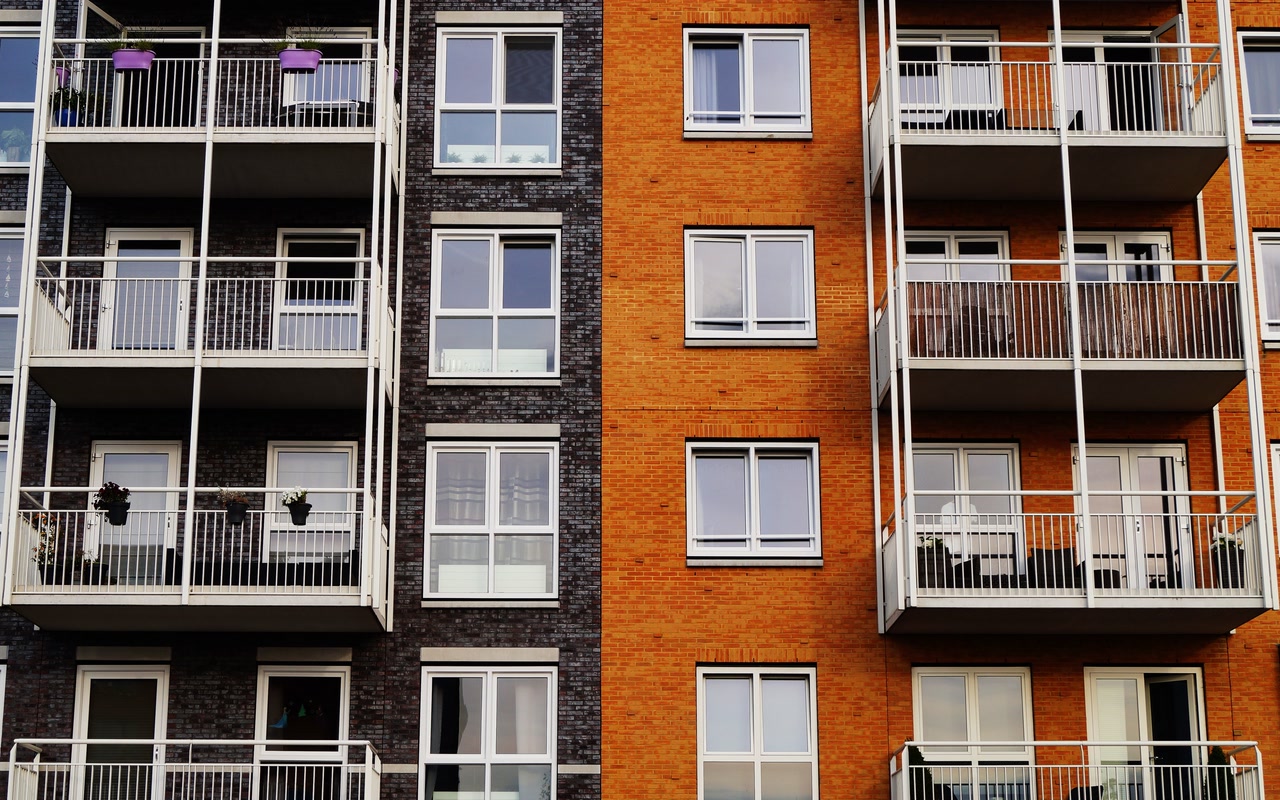 Detailed exterior of a modern orange and grey apartment building with balconies