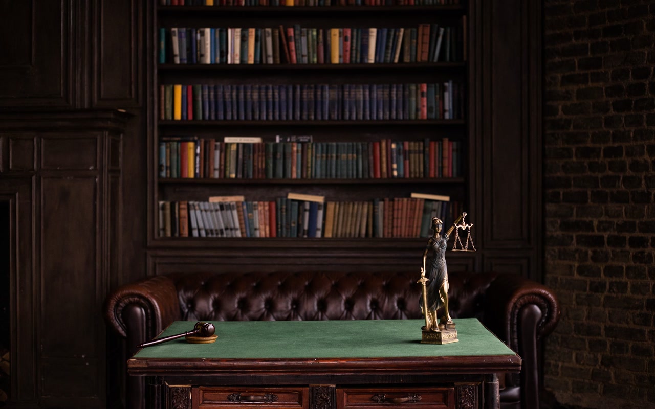 Lady Justice figurine and wooden gavel on a table in a book-lined study