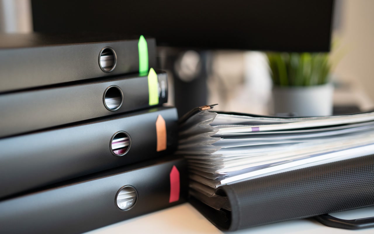 Stacked ring binders and generic documents arranged on an office desk