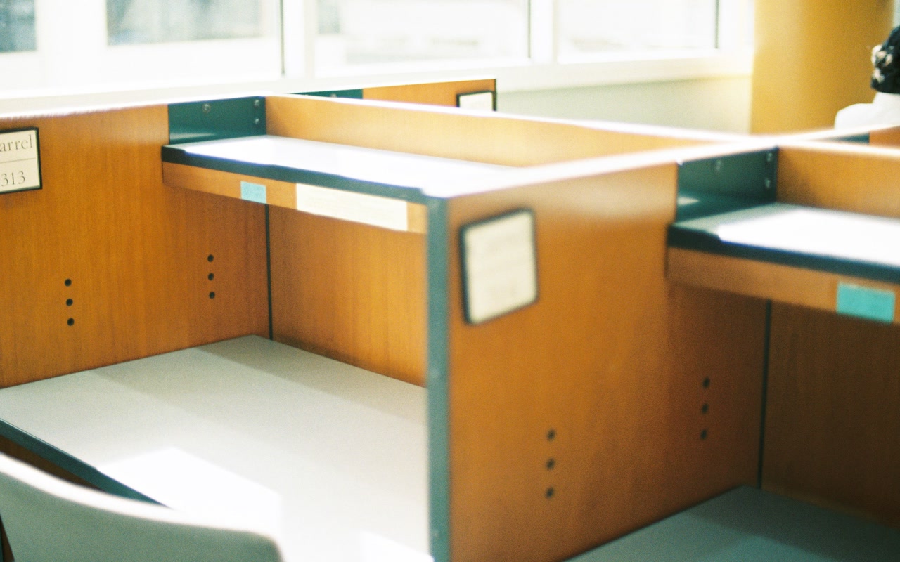 Empty wooden office cubicles beside a sunlit window