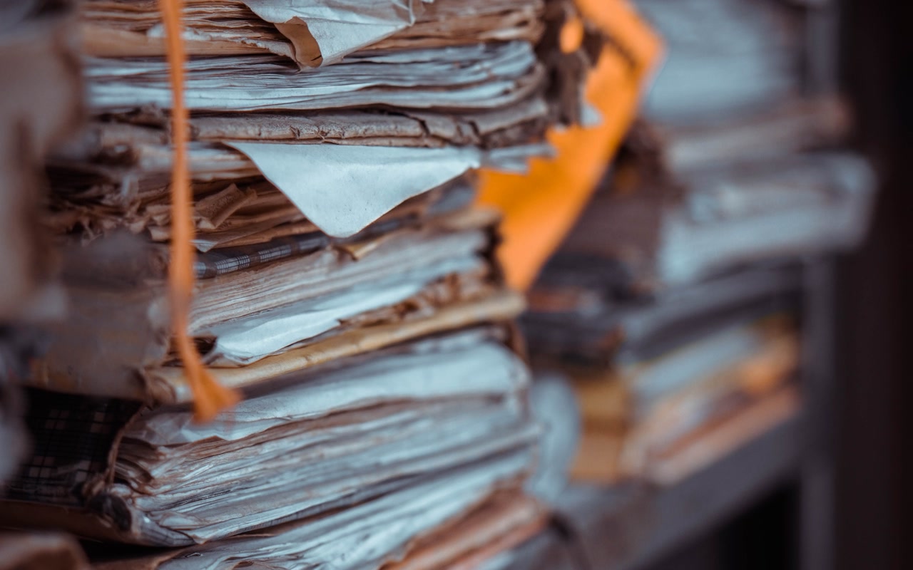 Stacks of paper records arranged across shelves in an office archive